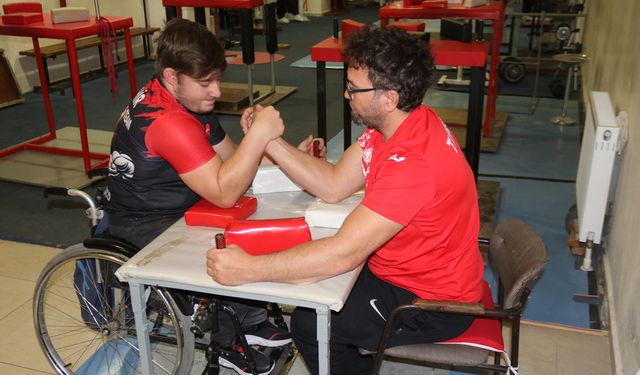 Aynı engele sahip olan öğrencisi ile bilek güreşi yapıyor
